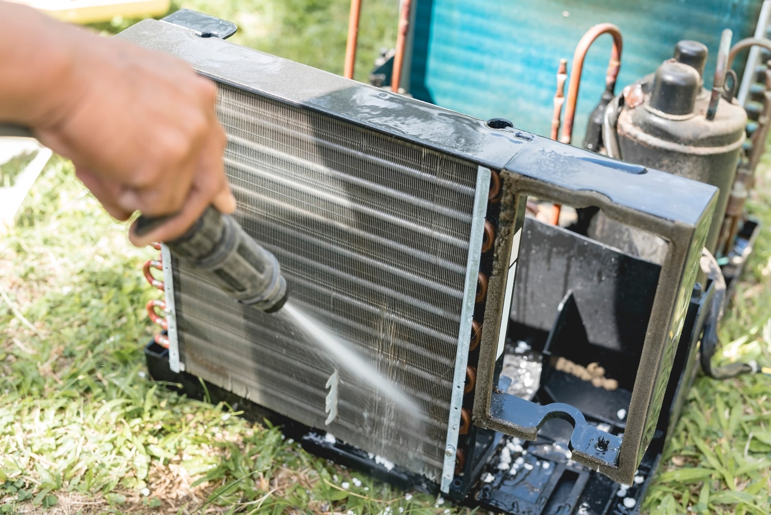 An AC coil being cleaned with a hose.