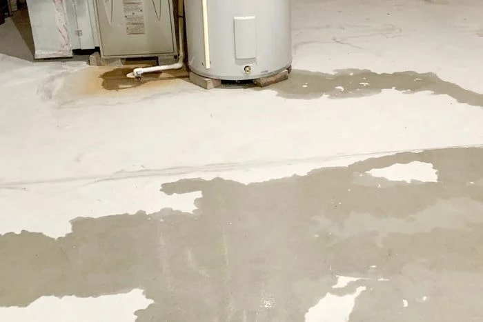 A furnace leaking water onto a basement floor.