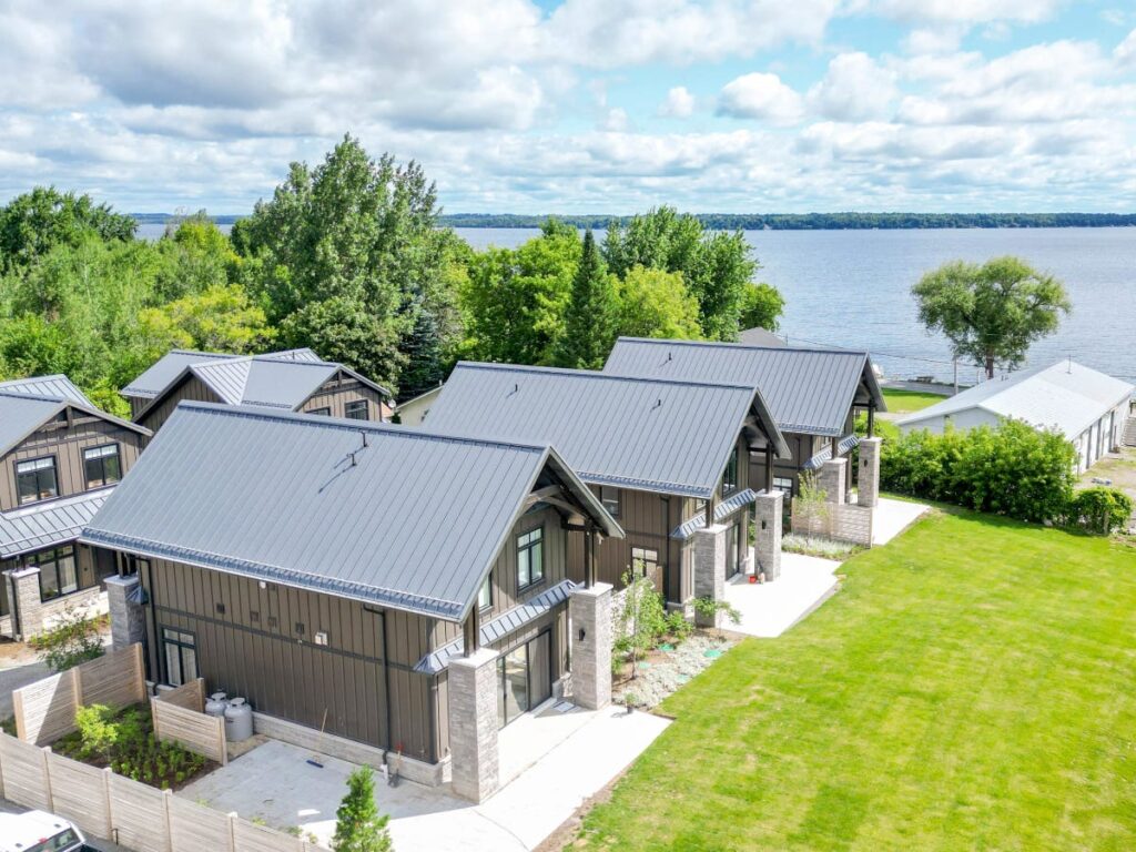 A set of modern lakeside cottages with a freshly mowed lawn.