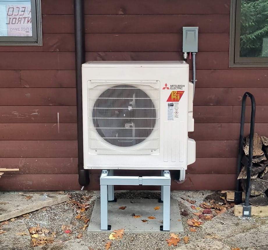 Mitsubishi ductless R454B Hyper-Heat outdoor on a cottage — shows brown track/lineset cover.