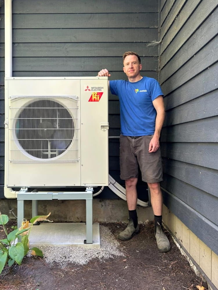Kawartha Eco Climate Control's Shane Switzer, beside Mitsubishi ductless outdoor with snow stand.