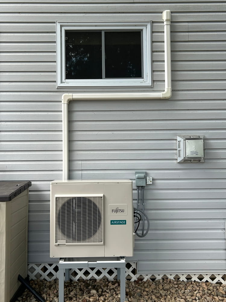 Fujitsu ductless outdoor unit with track — clean install with tidy line routing up and into the building.
