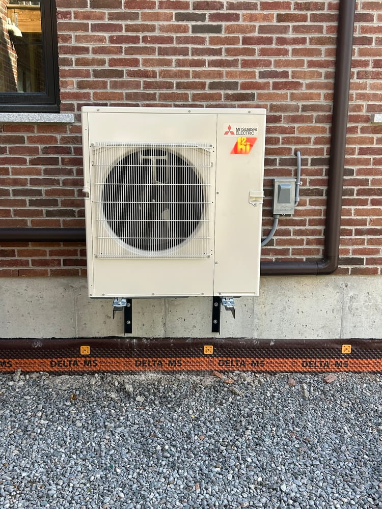 Mitsubishi ductless outdoor unit on wall brackets on a nice home (with brown line-hide/track).